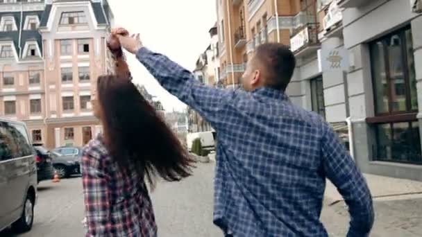 Romantische jongeren en liefde, man en vrouw als mannelijke en vrouwelijke studenten lopen en hand in hand in stadspark. Tilt shot, slow-motion — Stockvideo