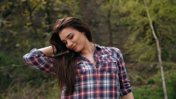 Mooie sexy brunette vrouw in geruit overhemd aanraken van haar en glimlachend — Stockvideo