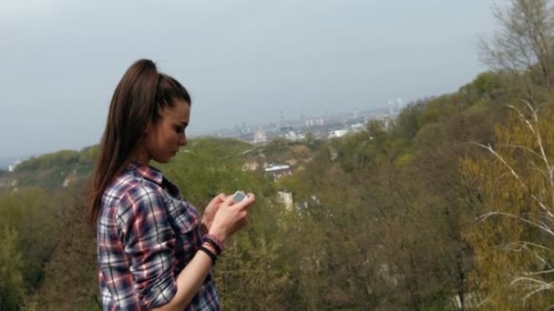 Joven morena tomando fotografías con smartphone a la vista de las atracciones turísticas de la naturaleza . — Vídeos de Stock