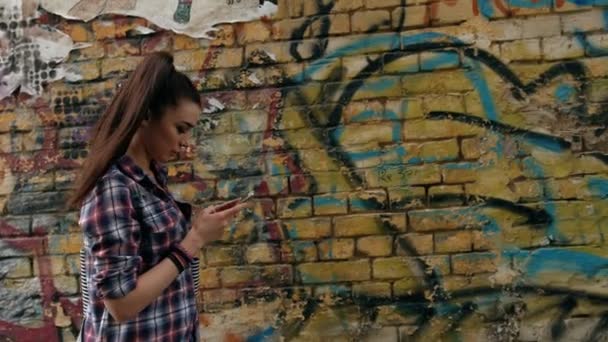 Leende brunett kvinna med en smart telefon gå på gatan på Sunny Day — Stockvideo