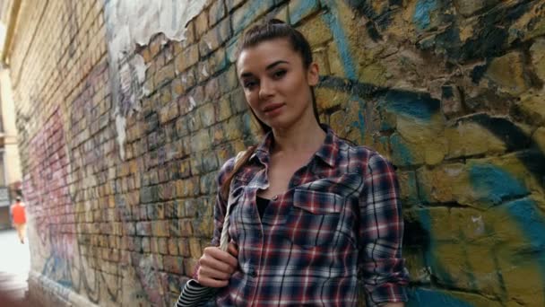 Porträtt av leende vacker mode kvinna i rutig skjorta mot vägg med abstrakt graffiti — Stockvideo
