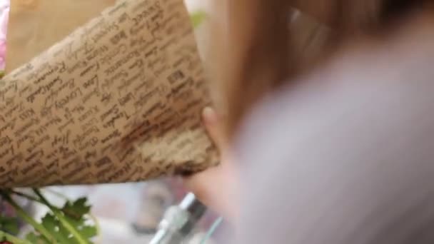 Woman putting flowers in a brown decorative paper. — Stock Video