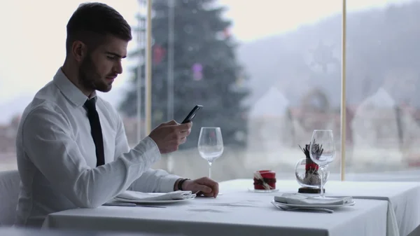 Bonito homem com telefone celular no restaurante — Fotografia de Stock
