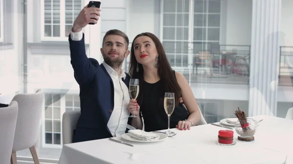 Couple joyeux prenant un selfie humoristique avec un smartphone au restaurant Photos De Stock Libres De Droits