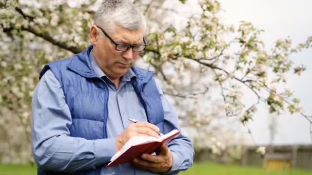 Akkerbouwer dragen glassses schrijven van notities. — Stockvideo