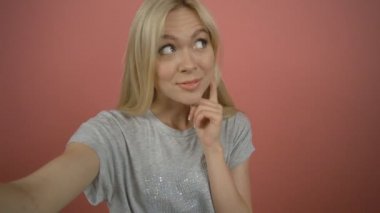 Gülümseyen genç sarışın kadın barış el hareketi ile selfie fotoğraf üzerinde pembe arka plan yapma