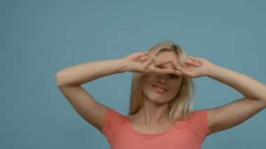 Eller yukarı, mavi stüdyo arka plan dans pembe elbise uydurma içinde genç ve güzel sarışın kadın