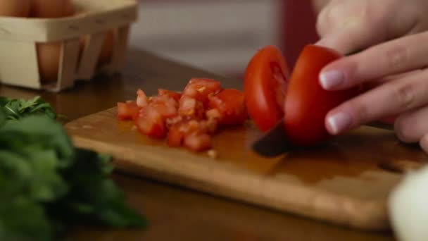 Слідкування за кадром жіночих рук з французькими цвяхами розрізають помідор на скибочки для приготування салату, зелені та овочів лежать на столі — стокове відео