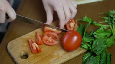 Bir kadın görüntüleri izleme eller Fransız çivi ile bir salata çatalı dilimlere domates kesme, yeşillik ve sebze yalan bir masada