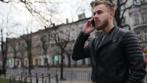 Knappe man praten over zijn telefoon in de straat. — Stockvideo