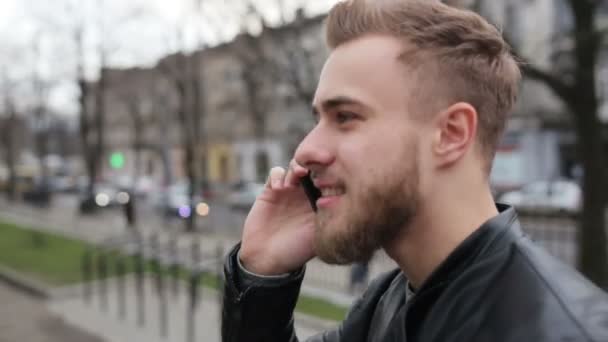 Mann diskutiert aktiv ein Thema am Telefon auf der Straße. — Stockvideo