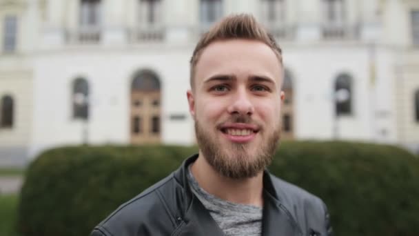 Vraiment drôle gars souriant sur une caméra et en utilisant son téléphone dans la rue . — Video