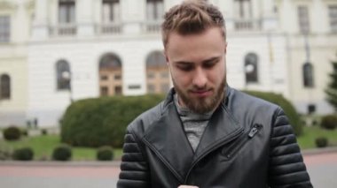 Kameradan saklamak için cep telefonunu kullanarak trendy kıyafetler giyen bir adam.