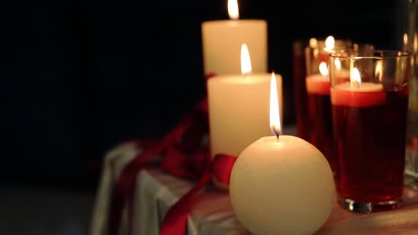 Luz pacífica de las velas de San Valentín para la cena en la mesa decorada con mantel y cintas rojas por la noche — Vídeo de stock