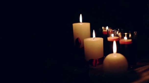 Gruppe brennender Kerzen mit roten Bändern auf schwarzem Hintergrund. — Stockvideo