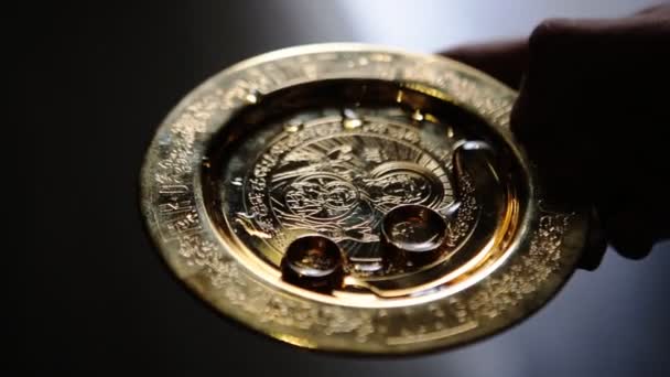 Close up of wedding rings of newlyweds during the consecration of holy water in the church before the wedding ceremony — Stock Video