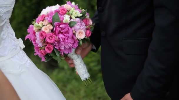 Närbild porträtt av glad bröllop par hålla rosa brudbukett och försiktigt kyssar, utomhus — Stockvideo
