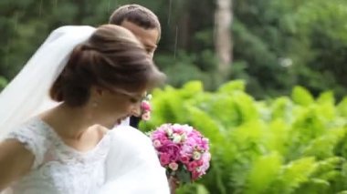 Mutlu evli çift süren sağanak yağmur altında ve gülüyor