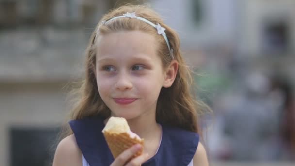 Kislány eszik fagylaltot egy forró, perzselő nyári nap a parkban, gyermek játszótér — Stock videók