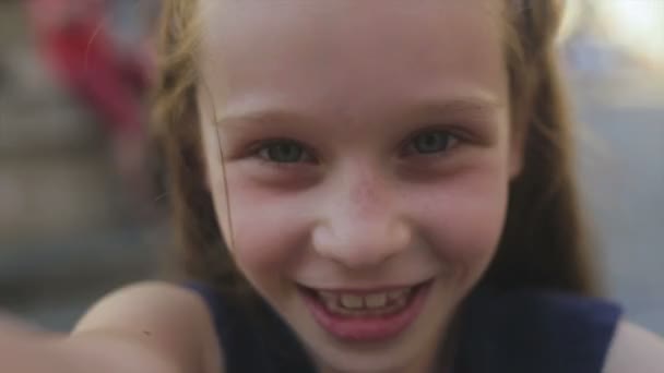 Крупним планом молода дівчина посміхається, коли вона дивиться в камеру — стокове відео