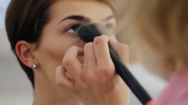 Makyaj sanatçı ile uygulanan toz kısa saç kesimi olan esmer kadın için fırça alıp yapmak