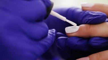 Kadın elinde bir güzellik tarafından beyaz manikür alma bir tırnak salonu yakın çekim