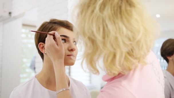 Professionell maskör med borste kosmetisk på ögonbryn av modell — Stockvideo