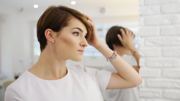 Beautiful brunette touching the ready short haircut in mirror. Concept of fashion and beauty — Stock Video