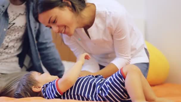 Retrato de padres jóvenes felices jugando con el bebé en la cama en casa — Vídeo de stock