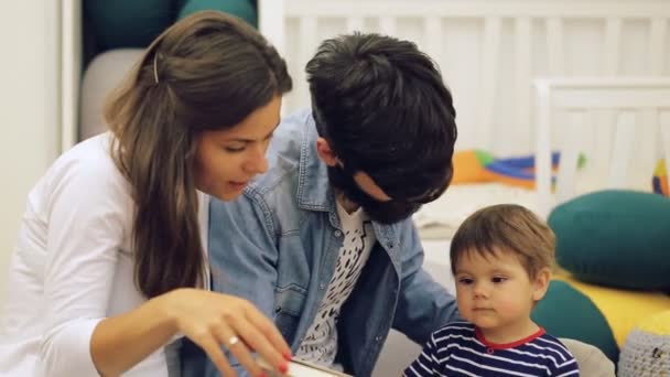 Family with baby boy sitting on floor at home and playing together — Stock Video