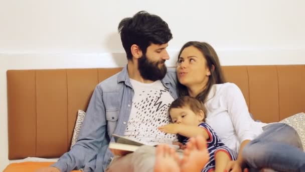 Šťastná rodina, matka, otec a jejich dítě číst knihu doma — Stock video