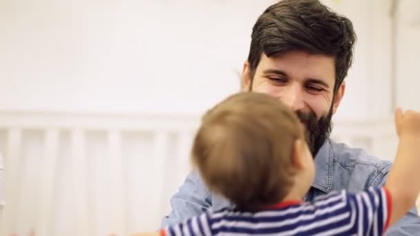 Vrolijke jongeman lift omhoog zijn trots van de baby in de slaapkamer, schoot thuis — Stockvideo