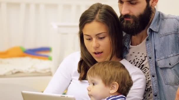 Familia joven y feliz con bebé niño usando tableta en el hogar moderno para jugar juegos y educación — Vídeo de stock