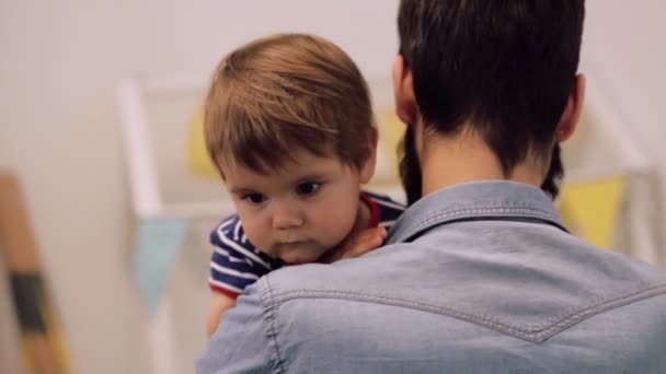 Jonge vader houdt zoon slaperige baby over zijn schouder hem het bed mee bezig — Stockvideo