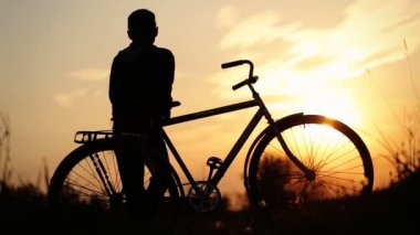 Onun Bisiklet sürme ve gün batımından güzelliği zevk küçük çocuk.