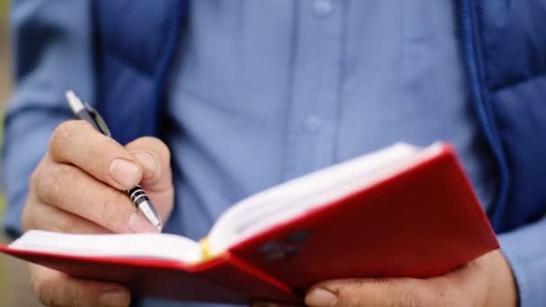 Close up of hands of a farmer writing notes in a notebook. — Stock Video