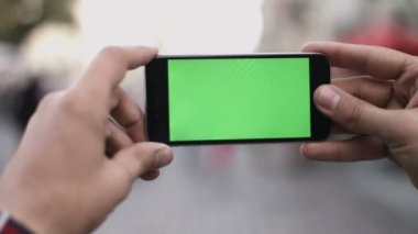 Akıllı telefon Held el yeşil ekran Chroma anahtar hareket izleme yatay tarafından. Telefon için el kuvvetli darbe aşağı-yukarı animasyon türü yakınlaştırma oturan kişi.