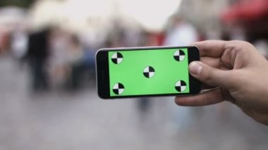 Akıllı telefon Held el yeşil ekran Chroma anahtar hareket izleme yatay tarafından. Telefon için el kuvvetli darbe aşağı-yukarı animasyon türü yakınlaştırma oturan kişi.