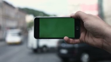 Akıllı telefon Held el yeşil ekran Chroma anahtar hareket izleme yatay tarafından. Telefon için el kuvvetli darbe aşağı-yukarı animasyon türü yakınlaştırma oturan kişi.