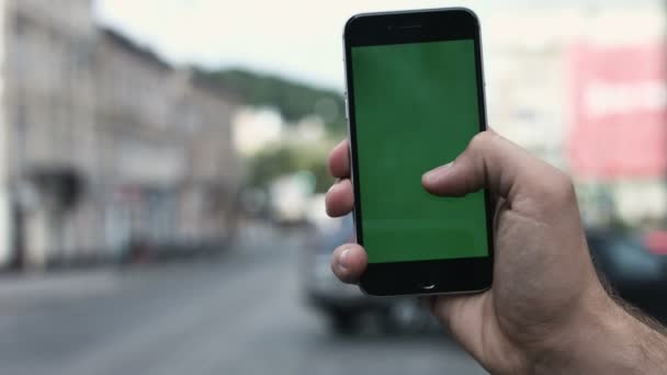 Un hombre sostiene un teléfono inteligente de pantalla verde contra Manhattans ocupado, tráfico de la 5ª Avenida . — Vídeos de Stock