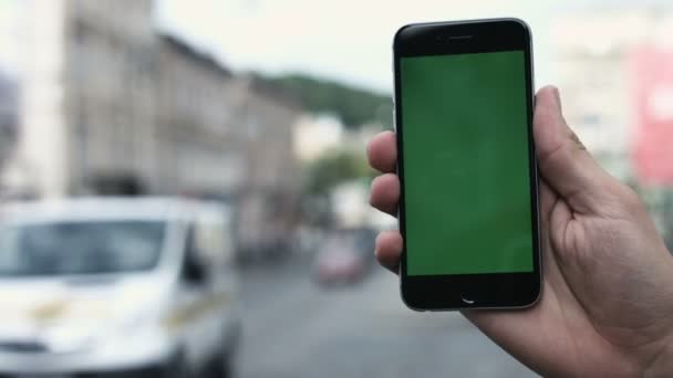 Un hombre sostiene un teléfono inteligente de pantalla verde contra Manhattans ocupado, tráfico de la 5ª Avenida . — Vídeos de Stock