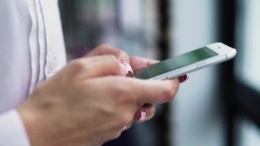 Bir iş kadını ellerinin akıllı telefona dokunması, yakın çekim mesajlaşması yan görünümü