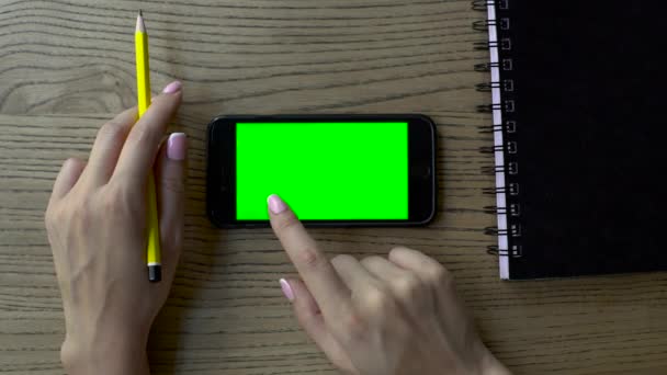 Gros plan des mains féminines tenant un crayon et touchant téléphone intelligent avec un doigt. Nouvelles technologies et concepts de style de vie . — Video