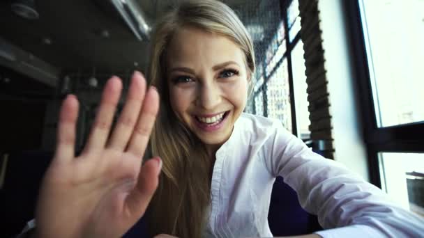 Joven rubia mostrando un gesto de saludo a alguien hablando por internet, primer plano — Vídeos de Stock