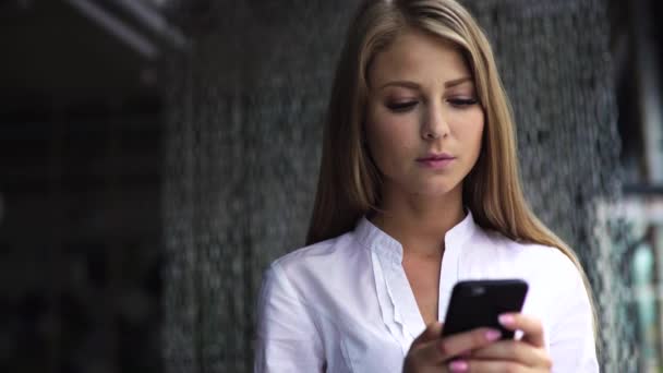 Joven mujer de negocios molesto mensaje de lectura blanca en el teléfono móvil de pie en el interior moderno espacio de oficina — Vídeos de Stock