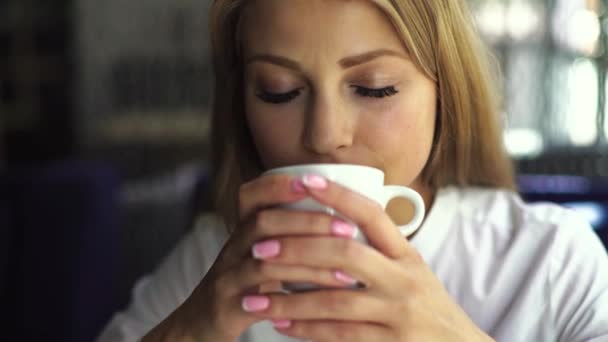 Närbild porträtt, ganska ung vacker blond kvinna med vit kopp kaffe — Stockvideo