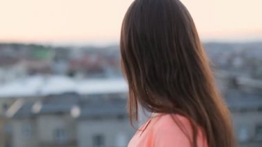 Güzel esmer model bir şehirde yürüyüş, saç rüzgarda hareket, uzağa bakarak ve kamera, nazik bir gülümseme veren., yakın çekim.