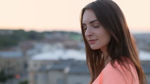 Mooie jonge Kaukasische brunette met lang haar meisje glimlachend op camera tegen wazig straat — Stockvideo