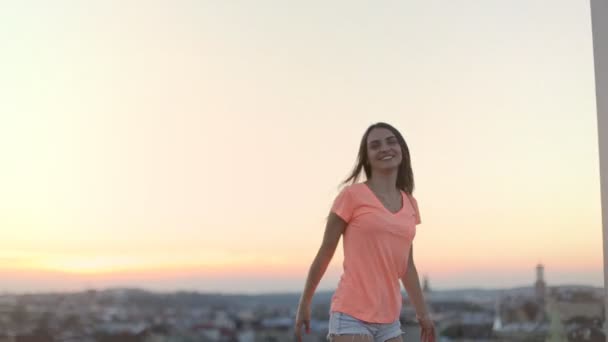 年轻女子跳跃和摇头，而享受在建筑露台，城市背景的肖像 — 图库视频影像