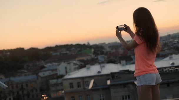 Turista encantador tirar fotos da cidade urbana ao pôr do sol, vista do telhado — Vídeo de Stock